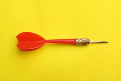 Photo of Red dart arrow on yellow background, top view