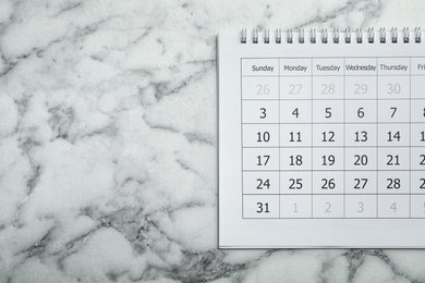 Paper calendar on marble background, top view. Space for text