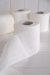 Photo of Soft toilet paper rolls on white wooden table