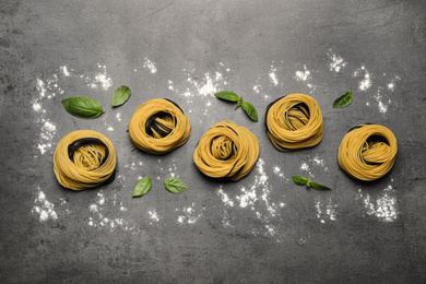 Photo of Raw linguine pasta with basil on grey table, flat lay