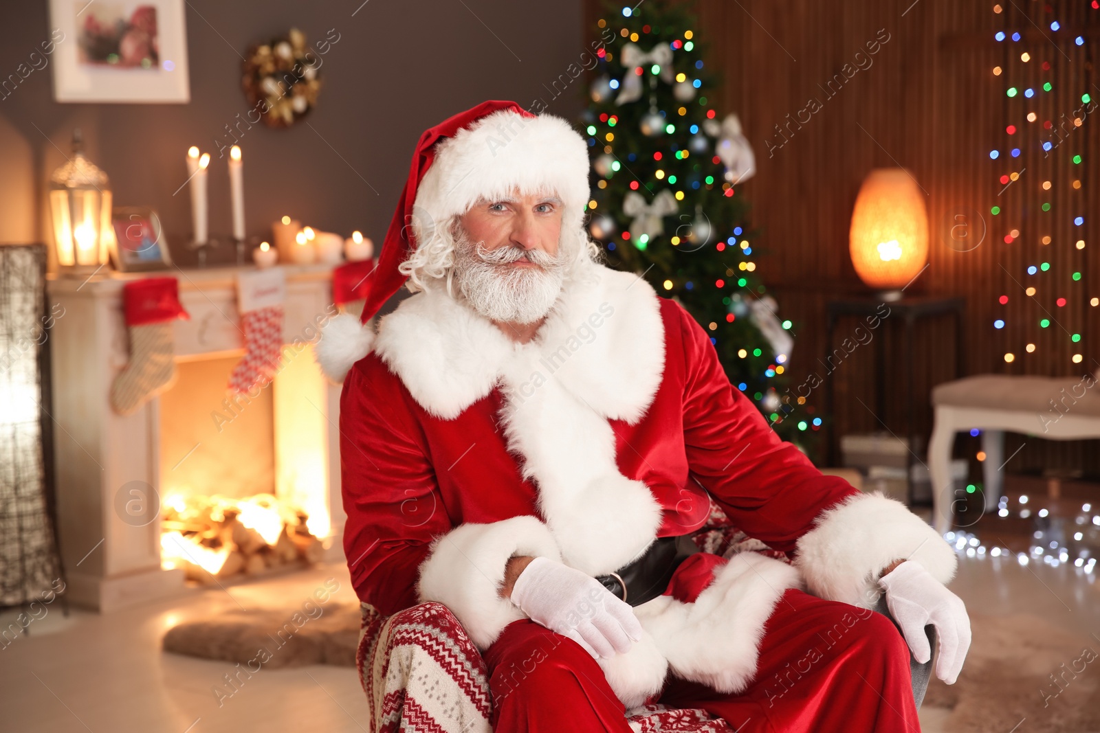 Photo of Santa Claus sitting in armchair at home. Christmas surprise for child