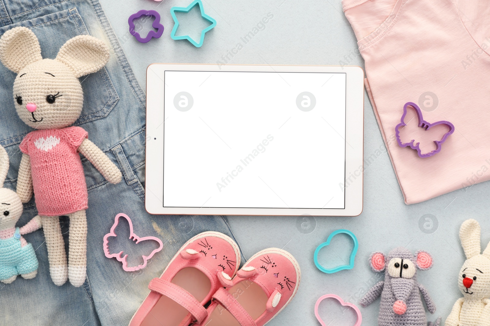 Photo of Modern tablet, clothes and toys on light grey background, flat lay. Space for text