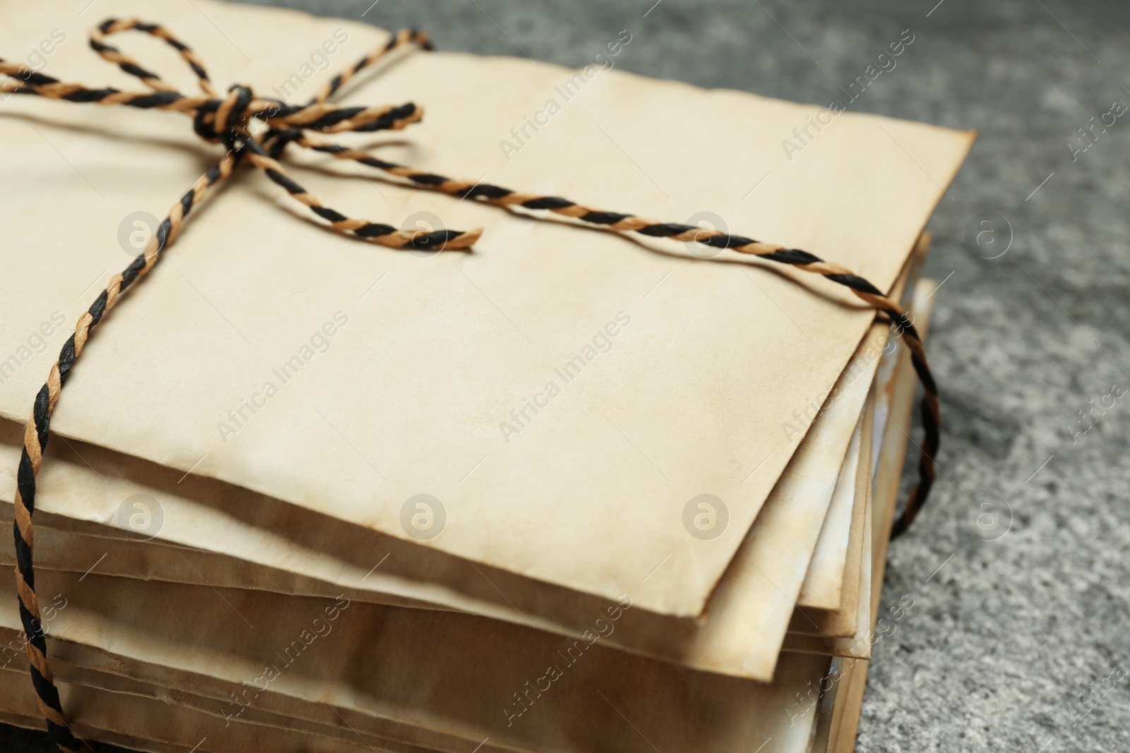 Photo of Stack of old letters tied with string on grey table, closeup