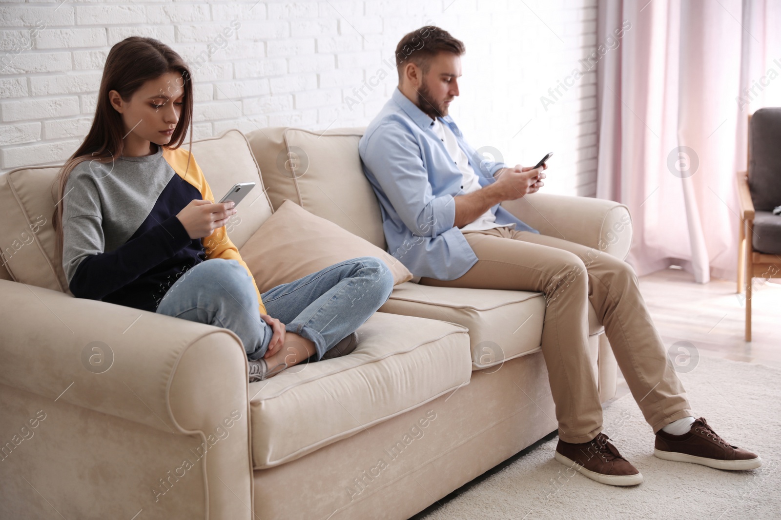 Photo of Couple addicted to smartphones ignoring each other at home. Relationship problems