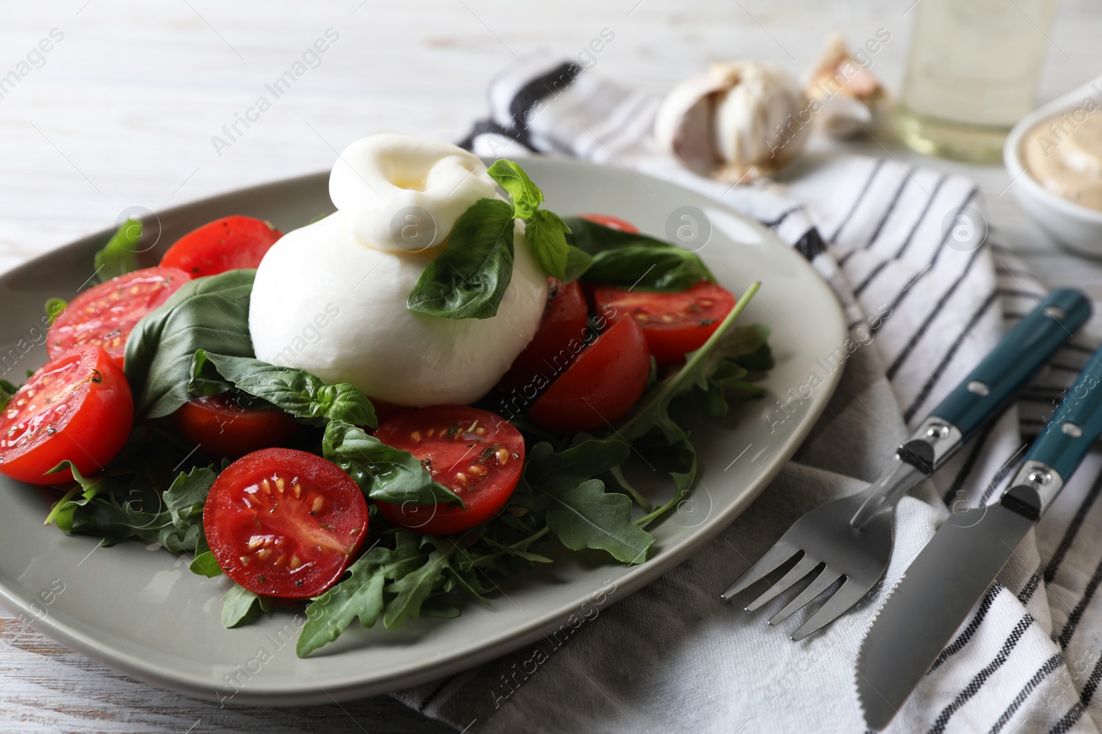 Photo of Delicious burrata cheese served with tomatoes and basil on white wooden table, closeup