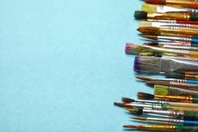 Photo of Different paint brushes on color background, closeup. Space for text