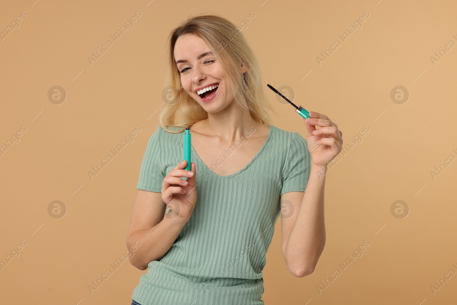 Photo of Beautiful woman with mascara on beige background