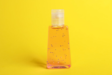 Photo of Bottle with antiseptic gel on yellow background