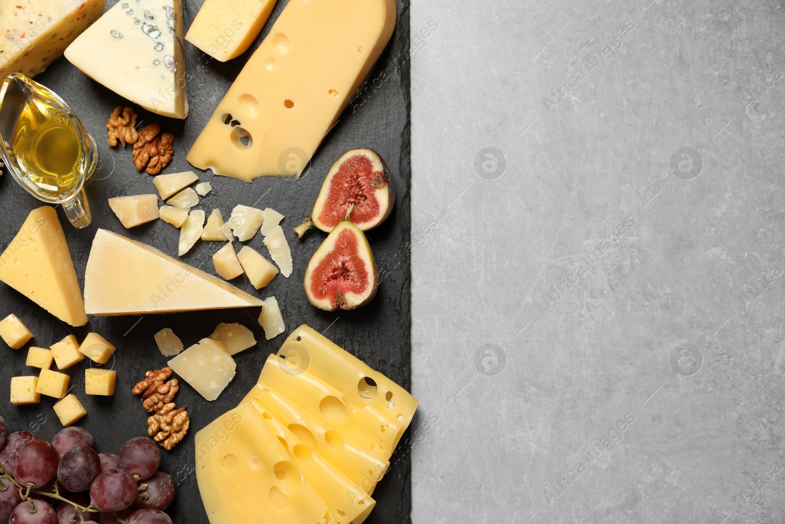 Photo of Different delicious cheeses served on grey table, top view. Space for text