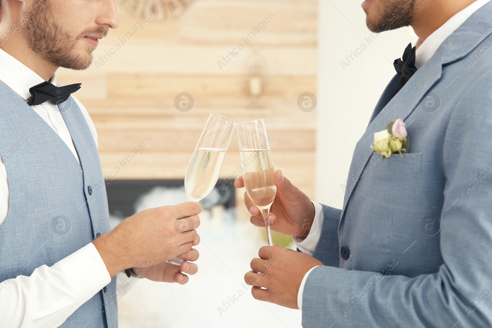 Photo of Newlywed gay couple with glasses of champagne at home, closeup