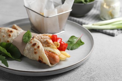 Delicious pita wrap with sausage, french fries and pepper on light gray table