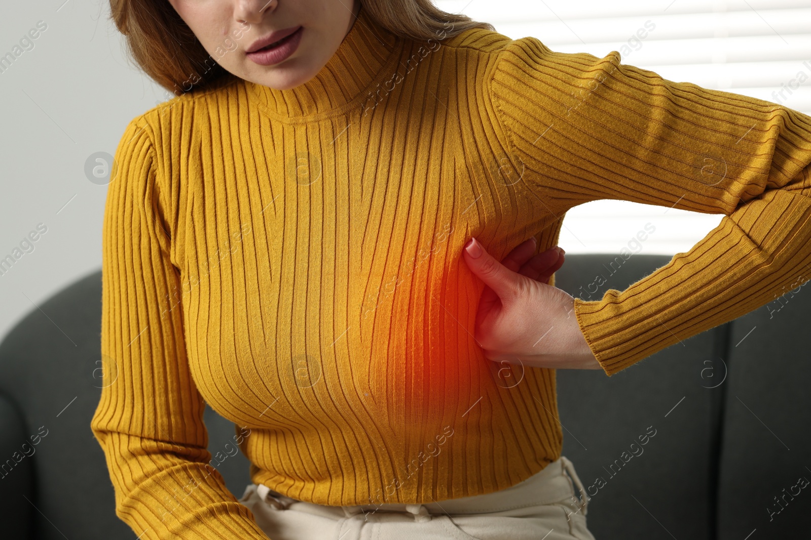 Image of Young woman suffering from breast pain at home, closeup