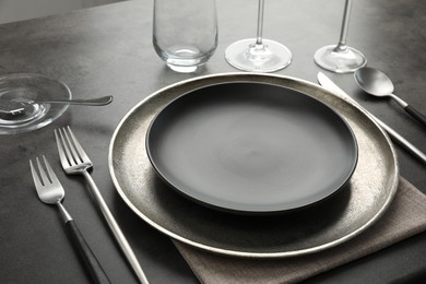 Photo of Stylish setting with cutlery, glasses and plates on black table