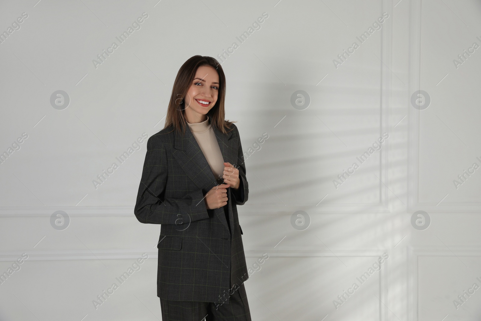 Photo of Portrait of beautiful young woman in fashionable suit near white wall, space for text. Business attire
