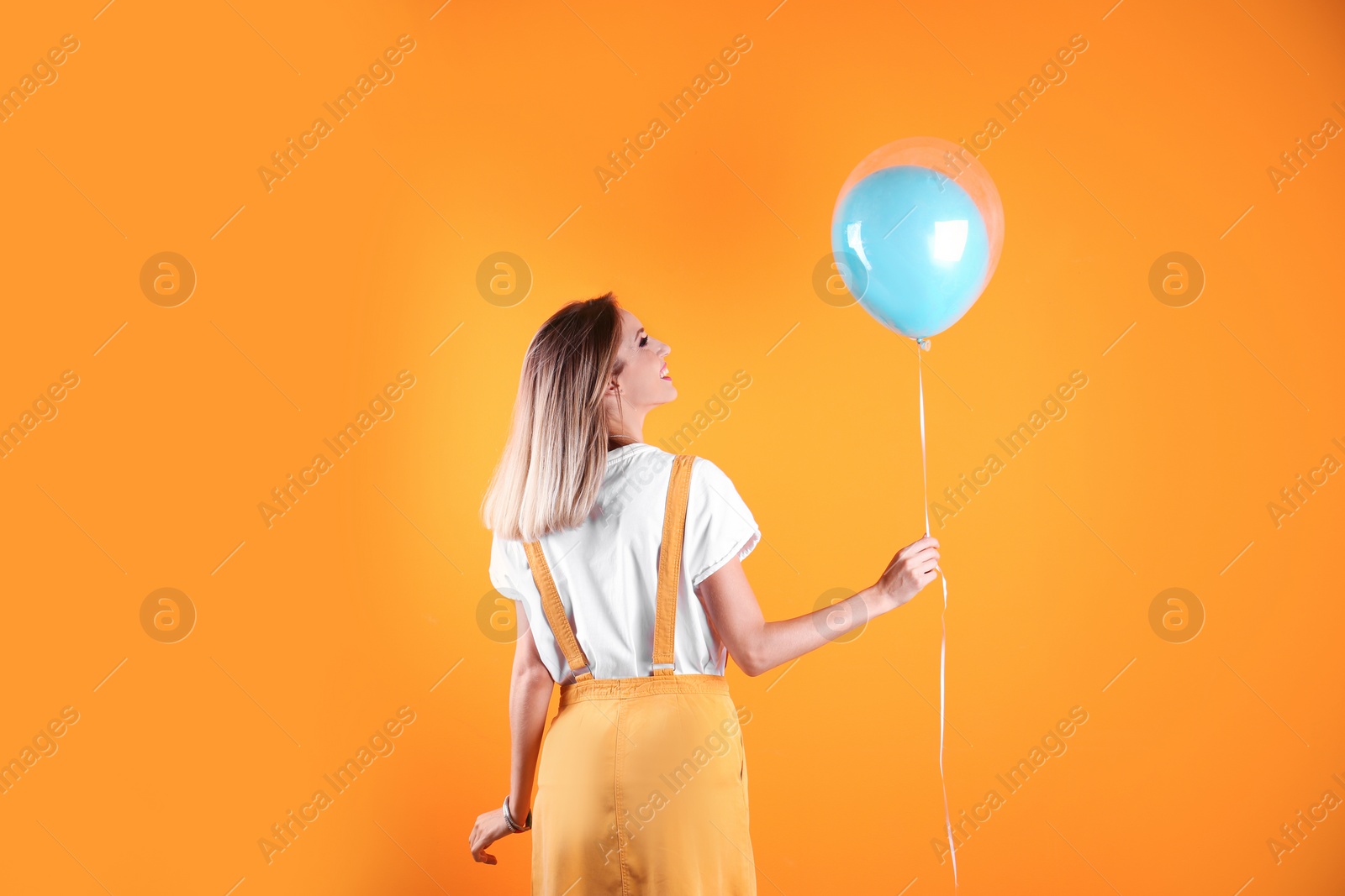Photo of Young woman with air balloon on color background