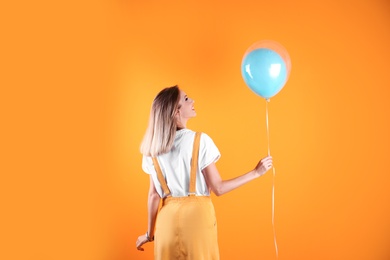 Young woman with air balloon on color background