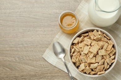 Photo of Bowl of sweet crispy breakfast cereal, milk and honey on wooden table, flat lay. Space for text