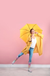 Woman with yellow umbrella near color wall