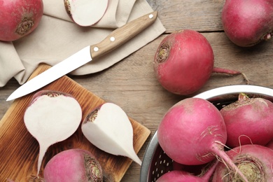 Photo of Red turnips and knife on wooden table, flat lay