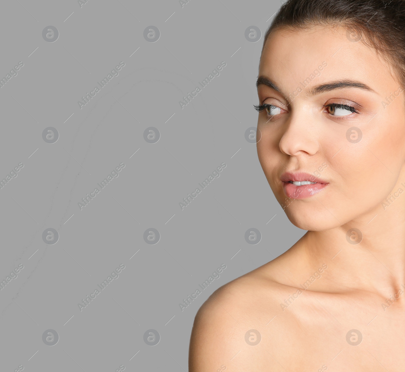 Photo of Young woman with beautiful makeup on grey background. Professional cosmetic products