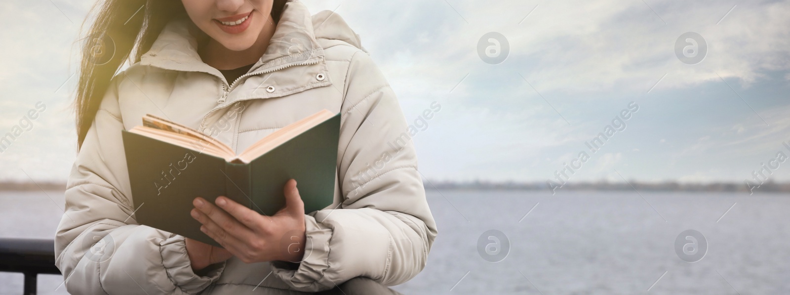 Image of Woman reading book near river on cloudy day, space for text. Banner design