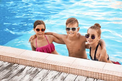 Happy children in swimming pool on sunny day