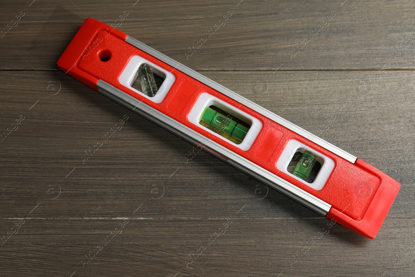 Photo of Red building level on wooden table, top view