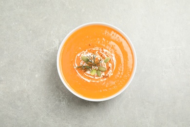 Photo of Delicious pumpkin soup in bowl on grey table, top view