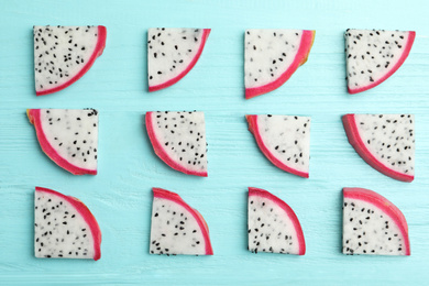 Photo of Slices of delicious dragon fruit (pitahaya) on light blue wooden table, flat lay