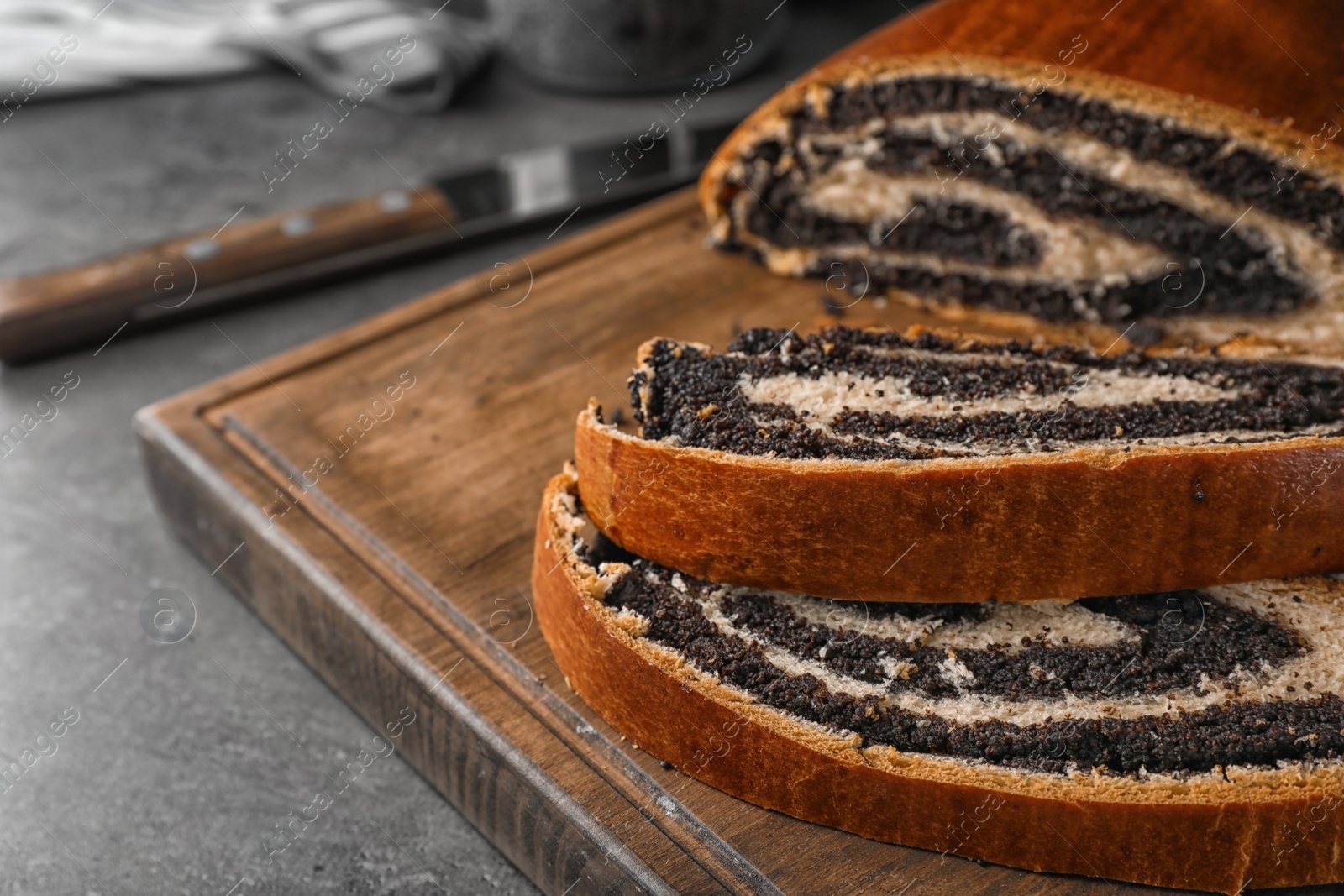 Photo of Cut tasty sweet bun with poppy seeds on gray table