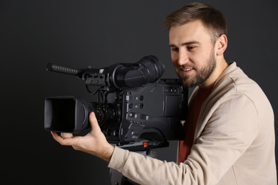 Operator with professional video camera on black background