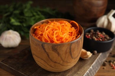 Photo of Delicious Korean carrot salad in bowl on wooden table