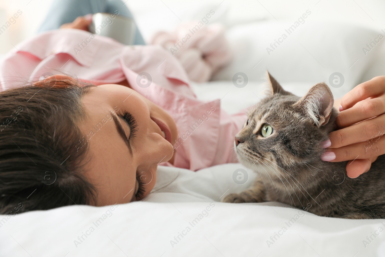 Photo of Young woman with cute cat on bed. Pet and owner