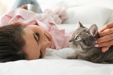 Photo of Young woman with cute cat on bed. Pet and owner