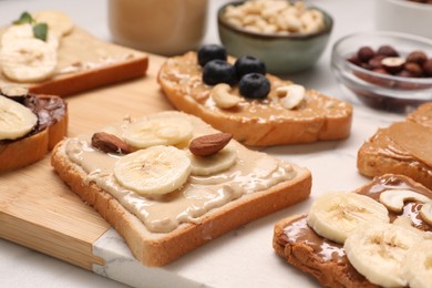Photo of Toasts with different nut butters, fruits and nuts on table, closeup