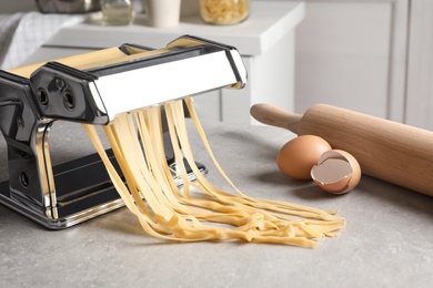 Photo of Pasta maker with dough on kitchen table