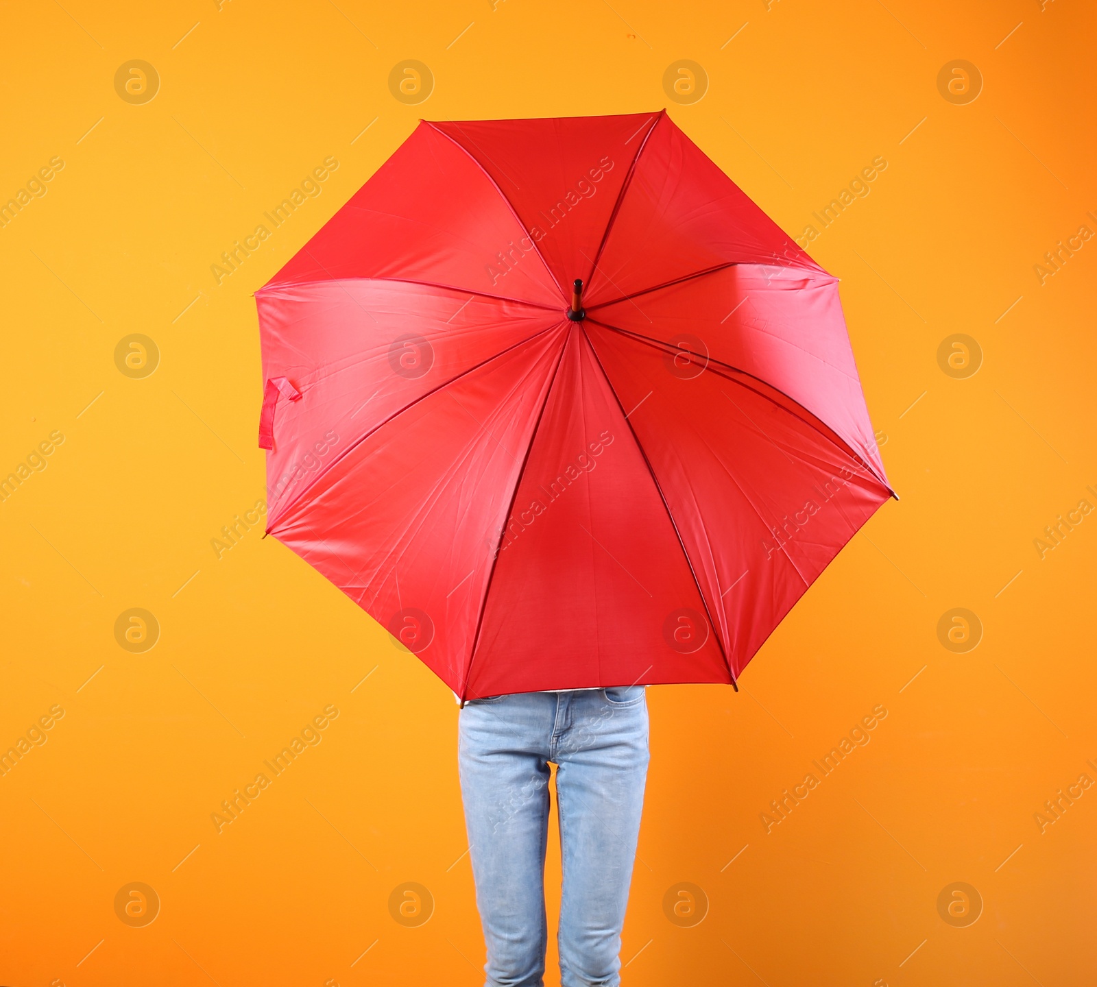 Photo of Woman hiding behind red umbrella on color background