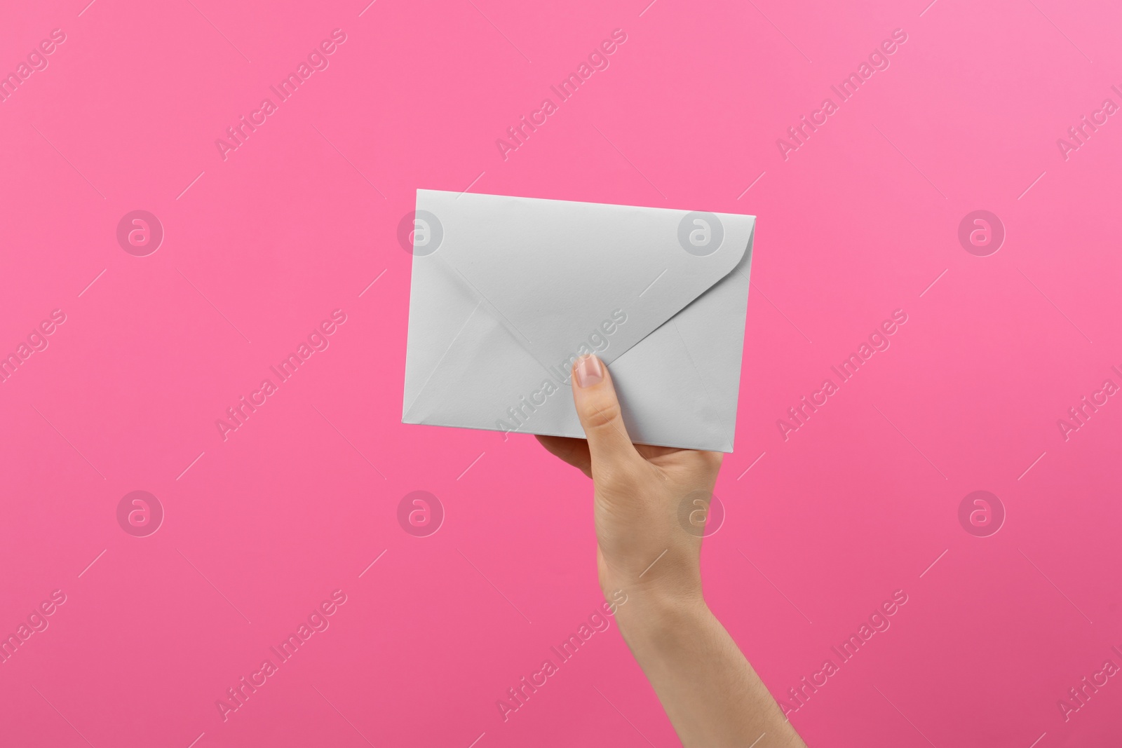 Photo of Woman holding white paper envelope on pink background, closeup