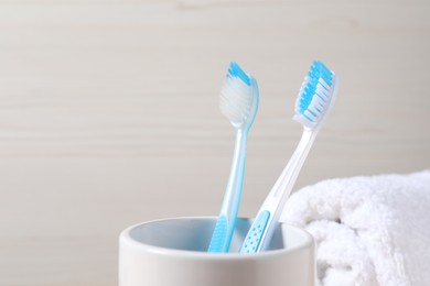 Photo of Plastic toothbrushes in holder against light background, closeup. Space for text