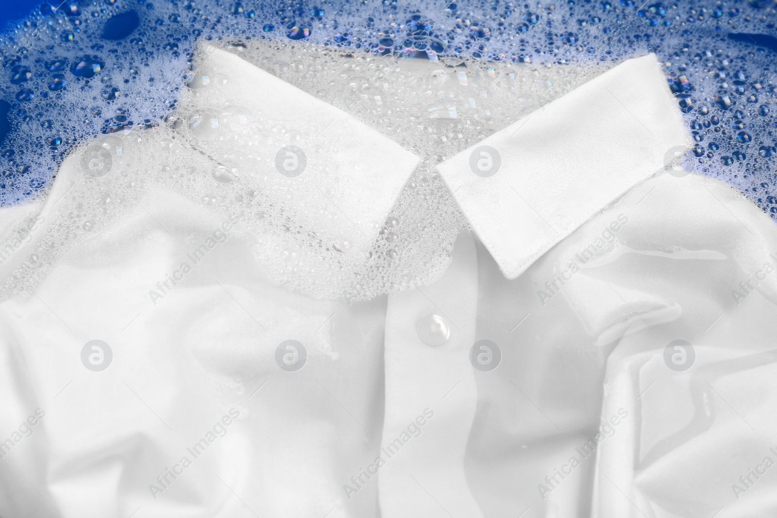 Photo of White shirt in suds, closeup. Hand washing laundry