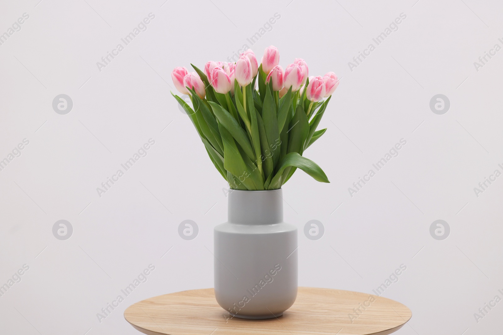Photo of Beautiful bouquet of fresh pink tulips on table against light background