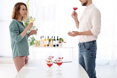 Photo of Young couple tasting wine at table indoors