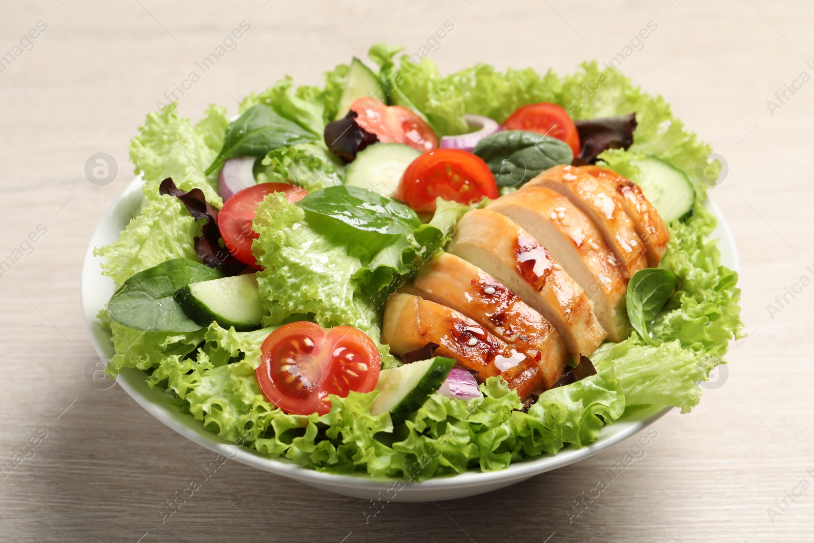 Photo of Delicious salad with chicken and vegetables on wooden table, closeup