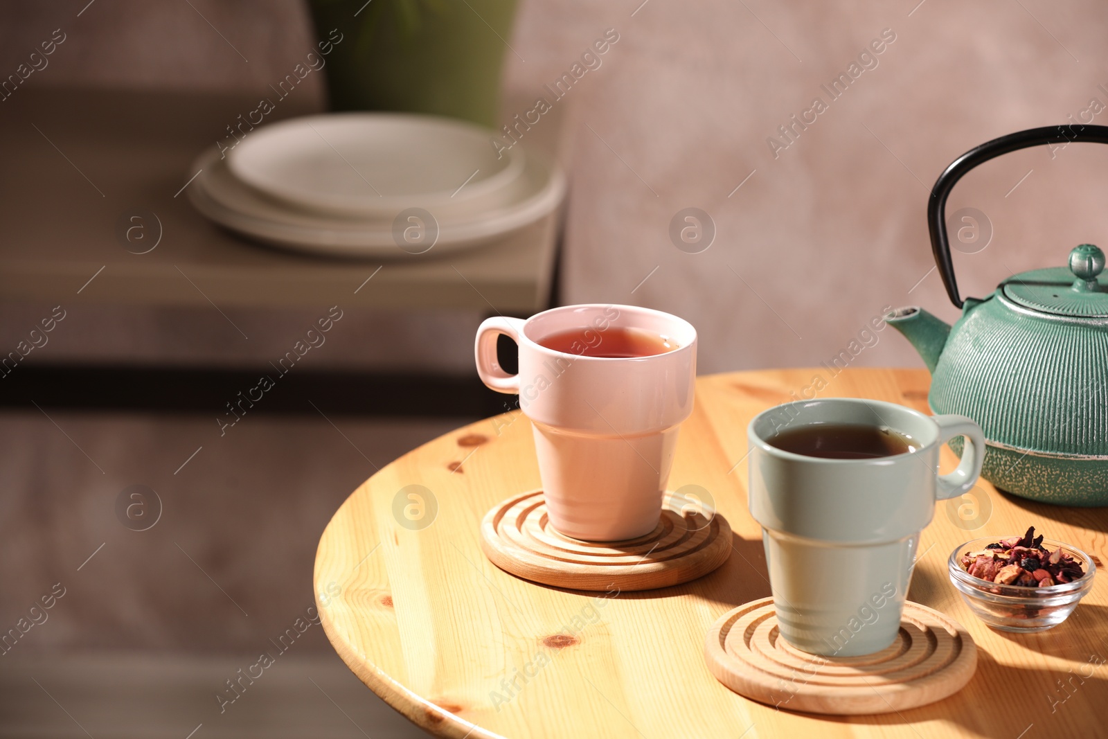 Photo of Aromatic tea, dry flower petals and teapot on wooden table, space for text