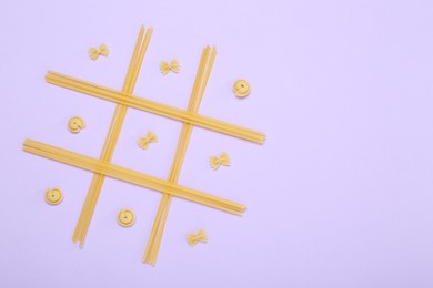 Photo of Tic tac toe game made with different types of pasta on lilac background, top view