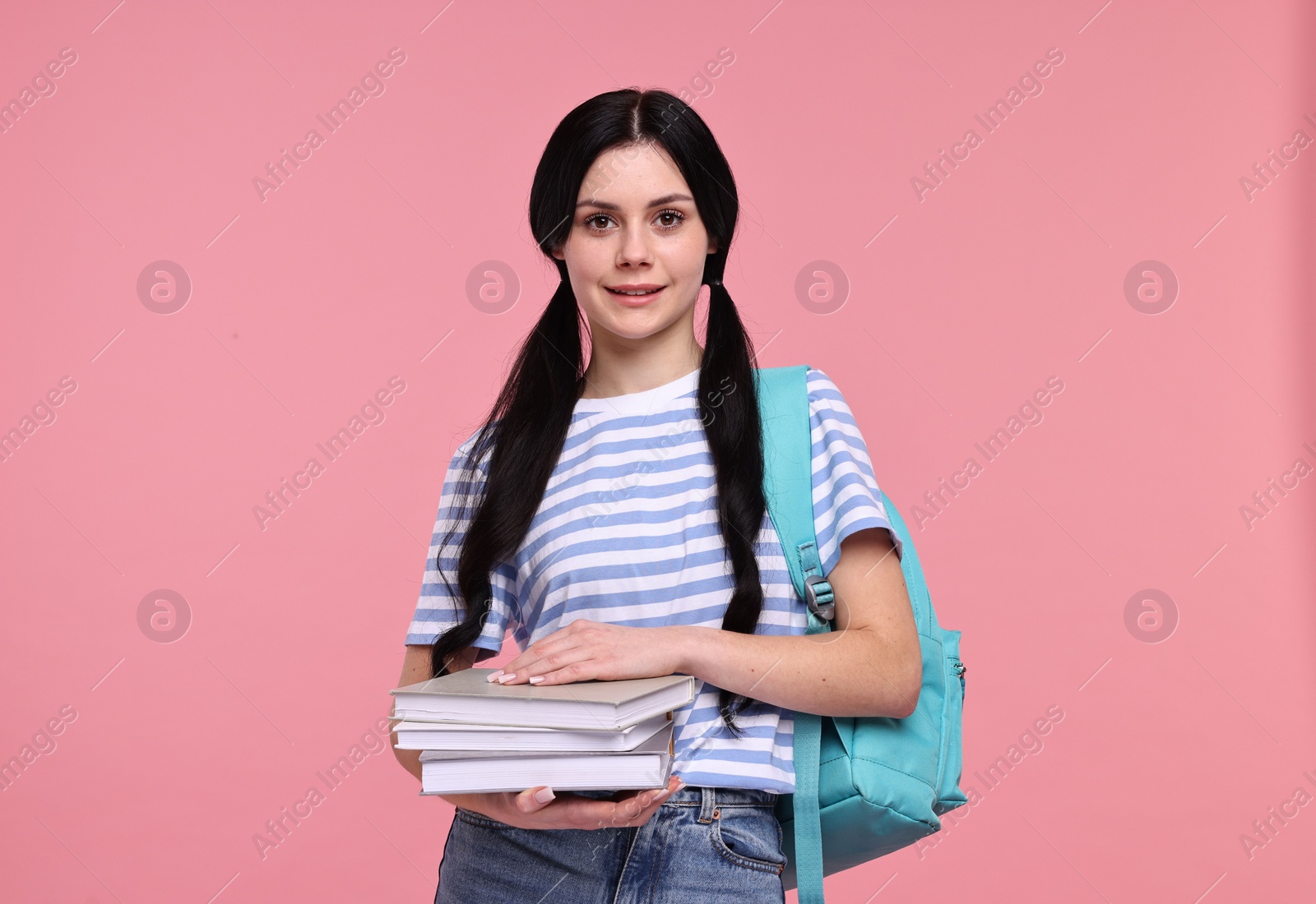 Photo of Smiling student with books and backpack on pink background