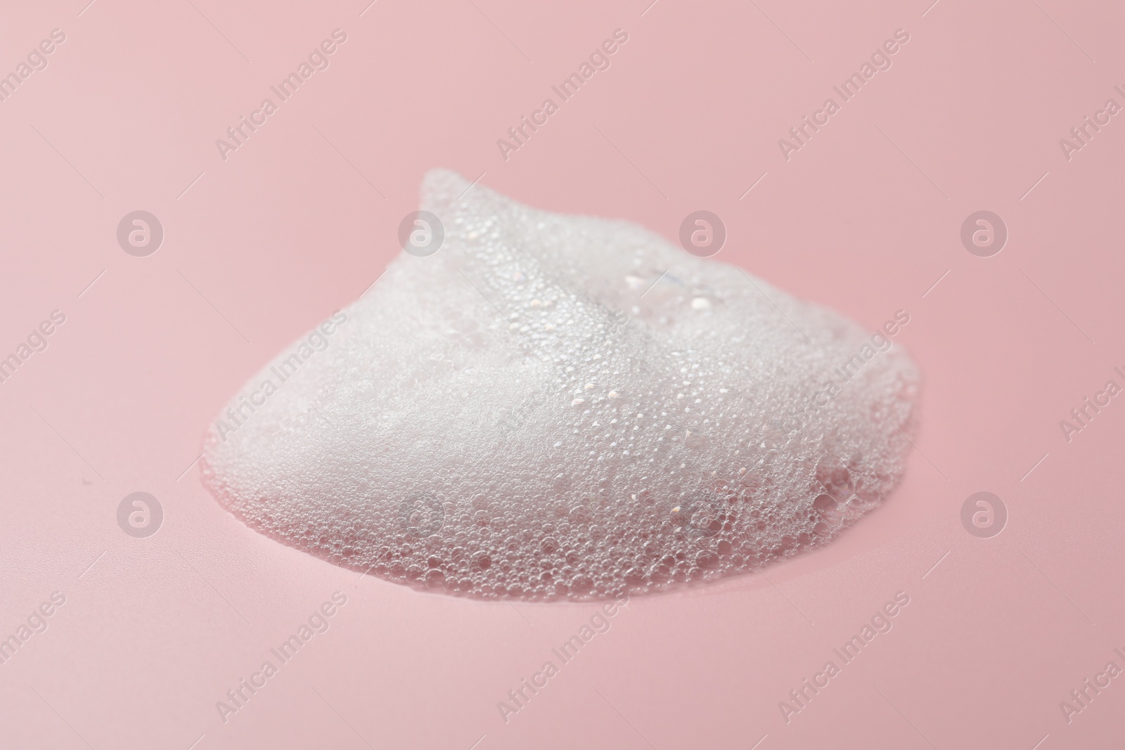 Photo of Drop of fluffy soap foam on pink background