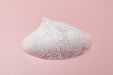 Photo of Drop of fluffy soap foam on pink background