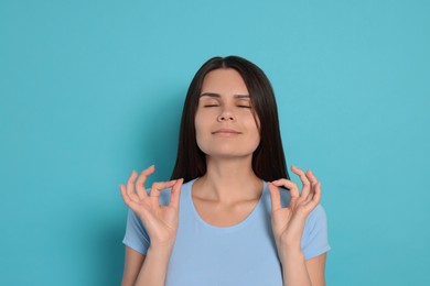 Photo of Young woman meditating on light blue background. Zen concept