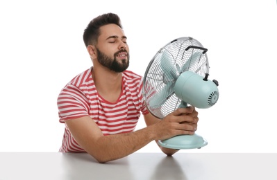 Photo of Man enjoying air flow from fan on white background. Summer heat